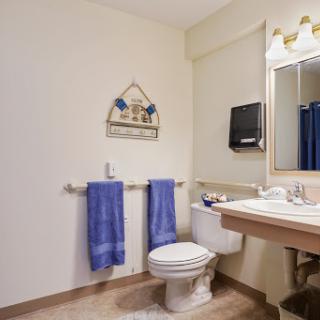 A neatly arranged bathroom featuring a toilet, sink, and blue towels.