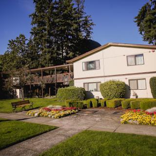 A well-maintained apartment complex surrounded by lush gardens and greenery on a sunny day.