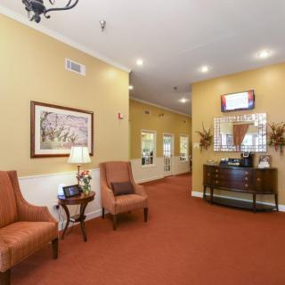 A warmly decorated hallway with chairs, a mirror, and artwork on the walls.