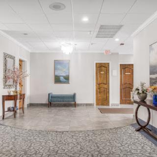 A welcoming lobby featuring a seating area, decorative artwork, and wooden doors.