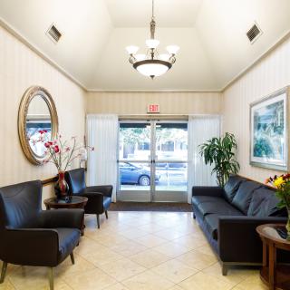 A well-lit lobby with black seating, decorative plants, and a chandelier.