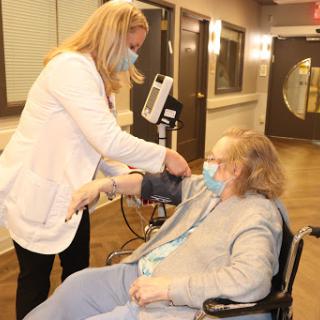 A healthcare professional checking the blood pressure of an elderly patient in a medical facility.