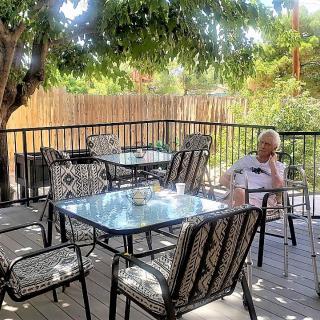 A peaceful outdoor patio with a person relaxing under the shade of trees.