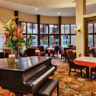 A cozy restaurant interior with a grand piano and elegant table settings.