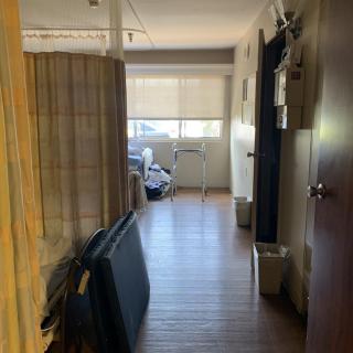 A hallway leading to a room with a large window and wooden flooring.