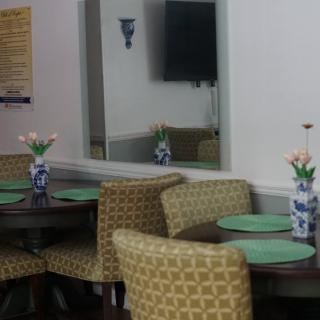 A cozy dining area with round tables, cushioned chairs, and decorative vases with flowers.