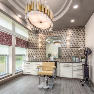 A luxurious salon interior featuring a stylish chandelier and barber chair.