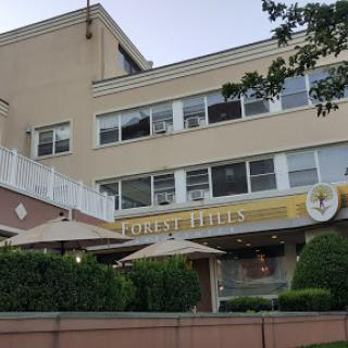 The exterior of a restaurant located in Forest Hills, featuring outdoor seating and an inviting sign.