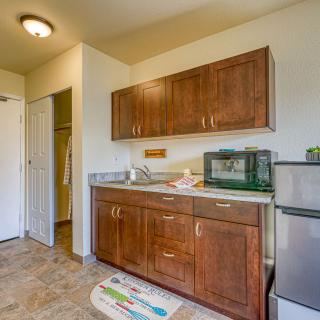 A small kitchen area with wooden cabinets, a refrigerator, and a microwave.
