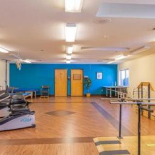 A spacious rehabilitation gym with exercise equipment and therapy tools.
