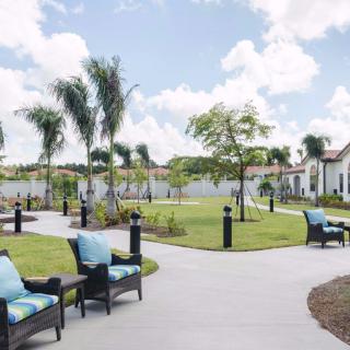 A serene outdoor garden with chairs and pathways under a partly cloudy sky.