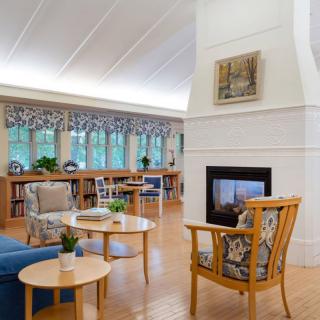 A cozy living room with modern furniture, featuring a central fireplace and ample natural light.