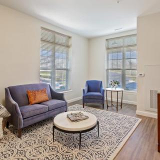 A cozy living room with a sofa, chair, and coffee table on a decorative rug.