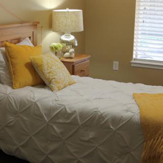 A cozy and inviting bedroom with a single bed, adorned with yellow pillows and a matching throw.