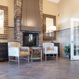 A modern living room with a stone fireplace, stylish chairs, and wooden flooring.