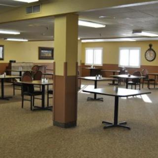 An empty restaurant dining area with carpeted flooring and neatly arranged tables and chairs.