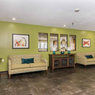 A modern lobby interior featuring two sofas, decorative artwork, and mirrors on a green accent wall.