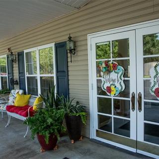 A cozy front porch with a bench, plants, and decorative glass doors.