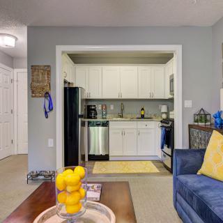 A cozy apartment living room with a view into the kitchen, featuring modern decor and bright accents.