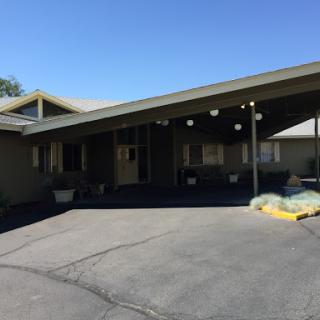 A view of a modern residential house with a covered porch and driveway under clear blue skies.