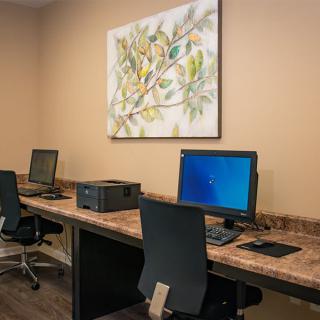 A small office setup with desks featuring computers and a printer, complemented by artwork on the wall.