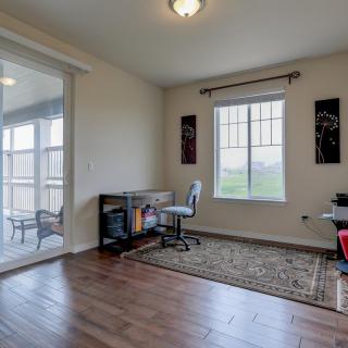 A well-lit home office with a desk and chair, featuring hardwood floors and decorative elements.
