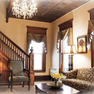 A vintage-style living room featuring a classic staircase, chandelier, and elegant furnishings.