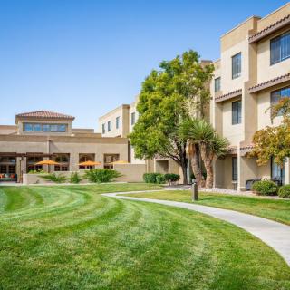 A modern residential building with a well-maintained lawn and pathway on a sunny day.
