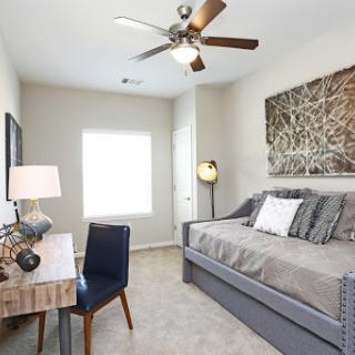 A modern and cozy bedroom featuring a stylish daybed, a workspace, and ample natural light.