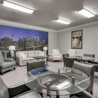A modern office lounge with comfortable seating arrangements and cityscape decor.
