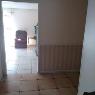 A view from a hallway into a room with tiled flooring and a chair.