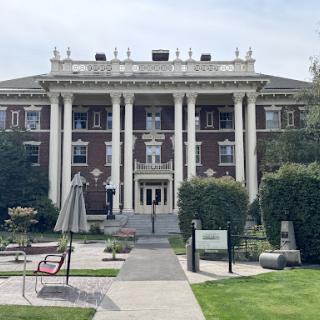 A grand historical building featuring classic architecture with prominent columns and a well-maintained landscape.