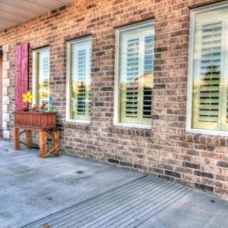A brick building exterior with windows featuring white shutters and a flower box.