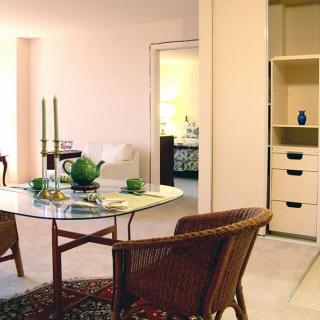 A cozy dining area with a glass table, wicker chairs, and decorative elements like candles and a teapot.