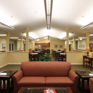 A well-lit library interior with a central couch and surrounding tables.