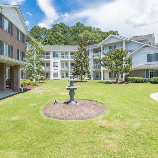 A well-maintained apartment building courtyard with a central fountain and lush greenery under a clear blue sky.