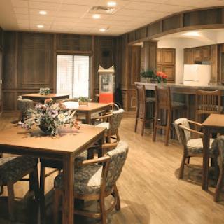 A cozy dining space featuring wooden tables and chairs, complemented by a modern kitchen area.