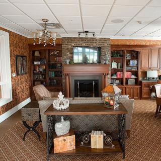 A cozy living room with wooden furniture and a fireplace, featuring bookshelves and decorative items.