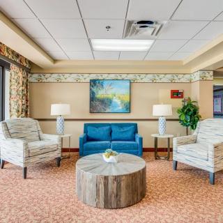 A cozy living room arrangement with a blue sofa, two patterned chairs, a round wooden table, and warm lighting.
