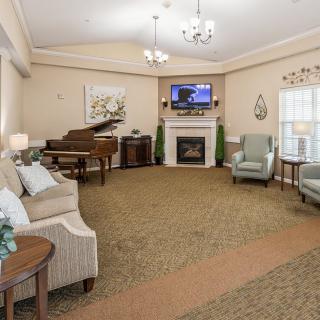A cozy living room with a grand piano and a fireplace, featuring elegant decor and comfortable seating.
