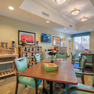 A cozy living room with a television, decorated with artwork and comfortable seating.
