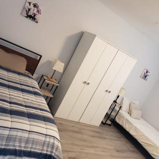 A cozy bedroom with two beds, a wardrobe, and a lamp.