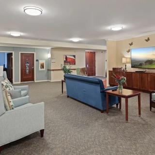 A spacious living room with comfortable seating, artwork on the walls, and ambient lighting.