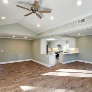Spacious open-concept living area with wood flooring and a kitchen view.