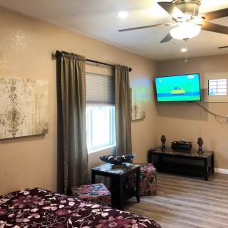Cozy bedroom featuring a ceiling fan, wall-mounted television, and stylish decor.