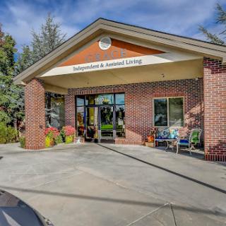 The welcoming entrance of a vibrant assisted living community, featuring outdoor seating and colorful planters.