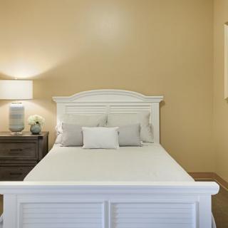 A cozy bedroom with a white bed and a nightstand with a lamp.