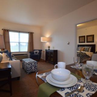 A cozy living room with a dining area, featuring comfortable seating and a neatly set table.
