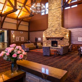 A cozy lobby area with a large stone fireplace, wooden ceilings, and comfortable seating.