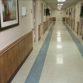 A long, well-lit hospital corridor with clean floors and artwork on the walls.